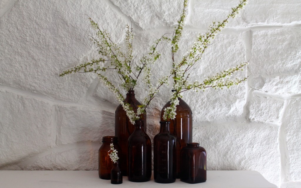 vintage amber bottles with spring blooms against stone