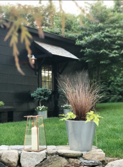 black garage with portico and plants plus a lantern with a candle