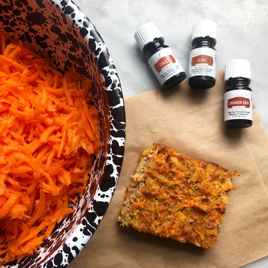 bowl with shredded carrot, essential oils, cake on brown parchment paper