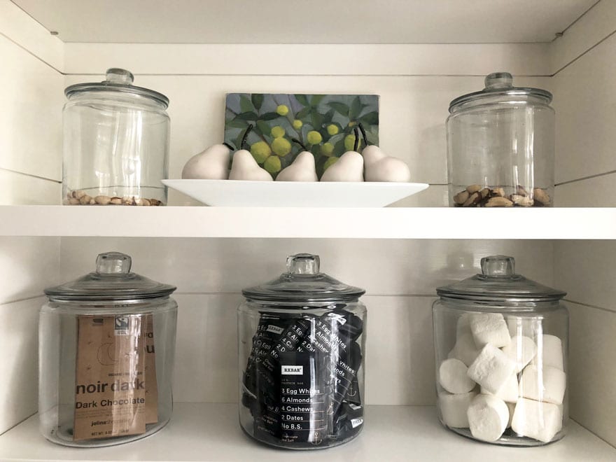 open pantry with glass jars filled with protein bars, nuts, marshmallows