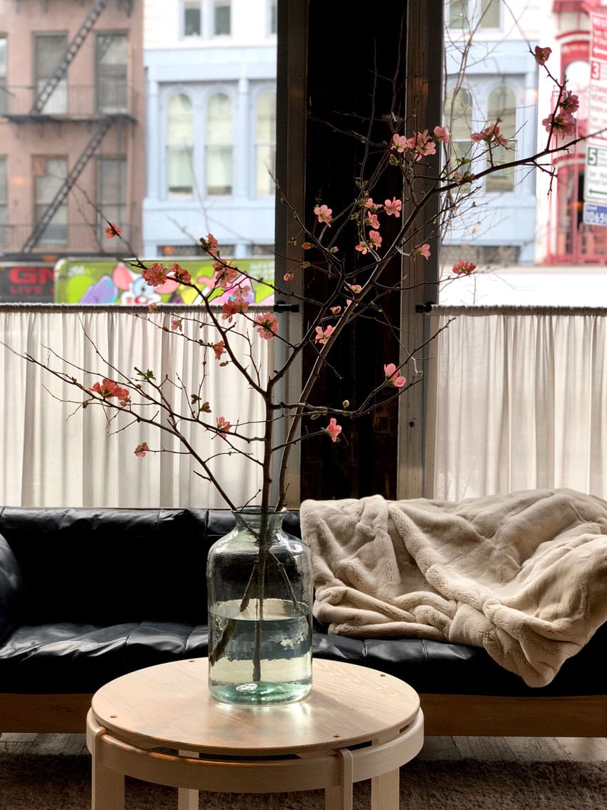 round table holding large glass jar of quince branches