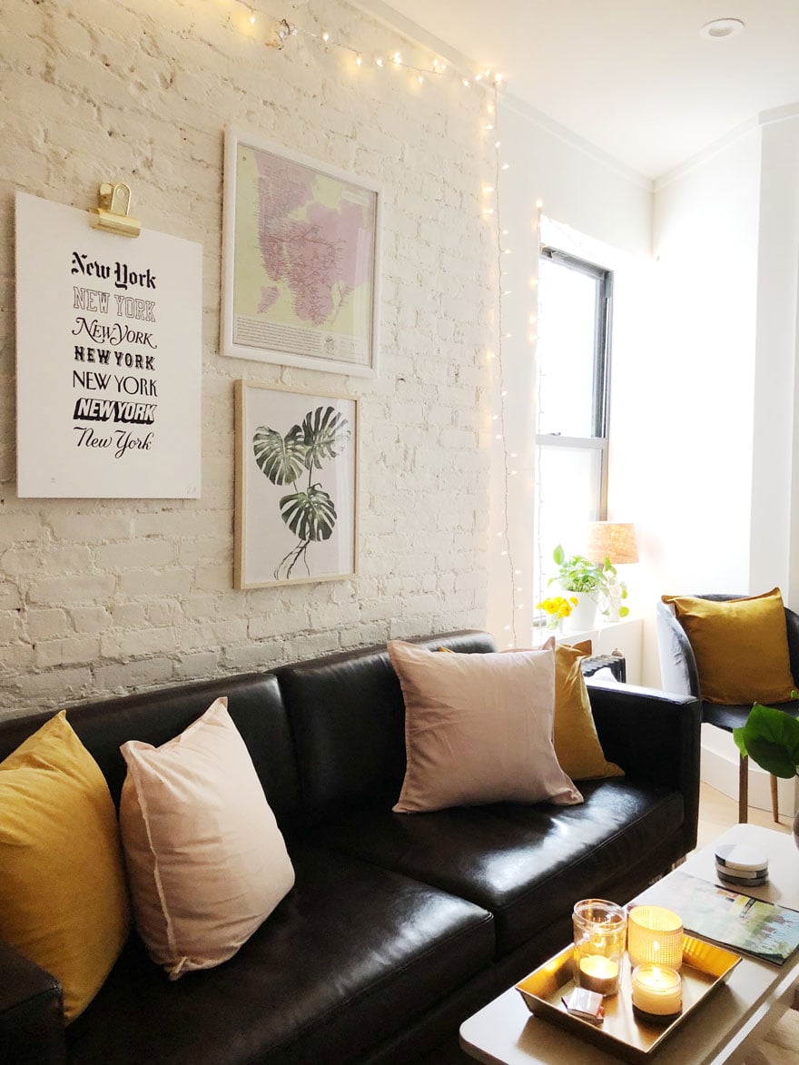 A sofa in front of an exposed brick wall with artwork hanging above it.