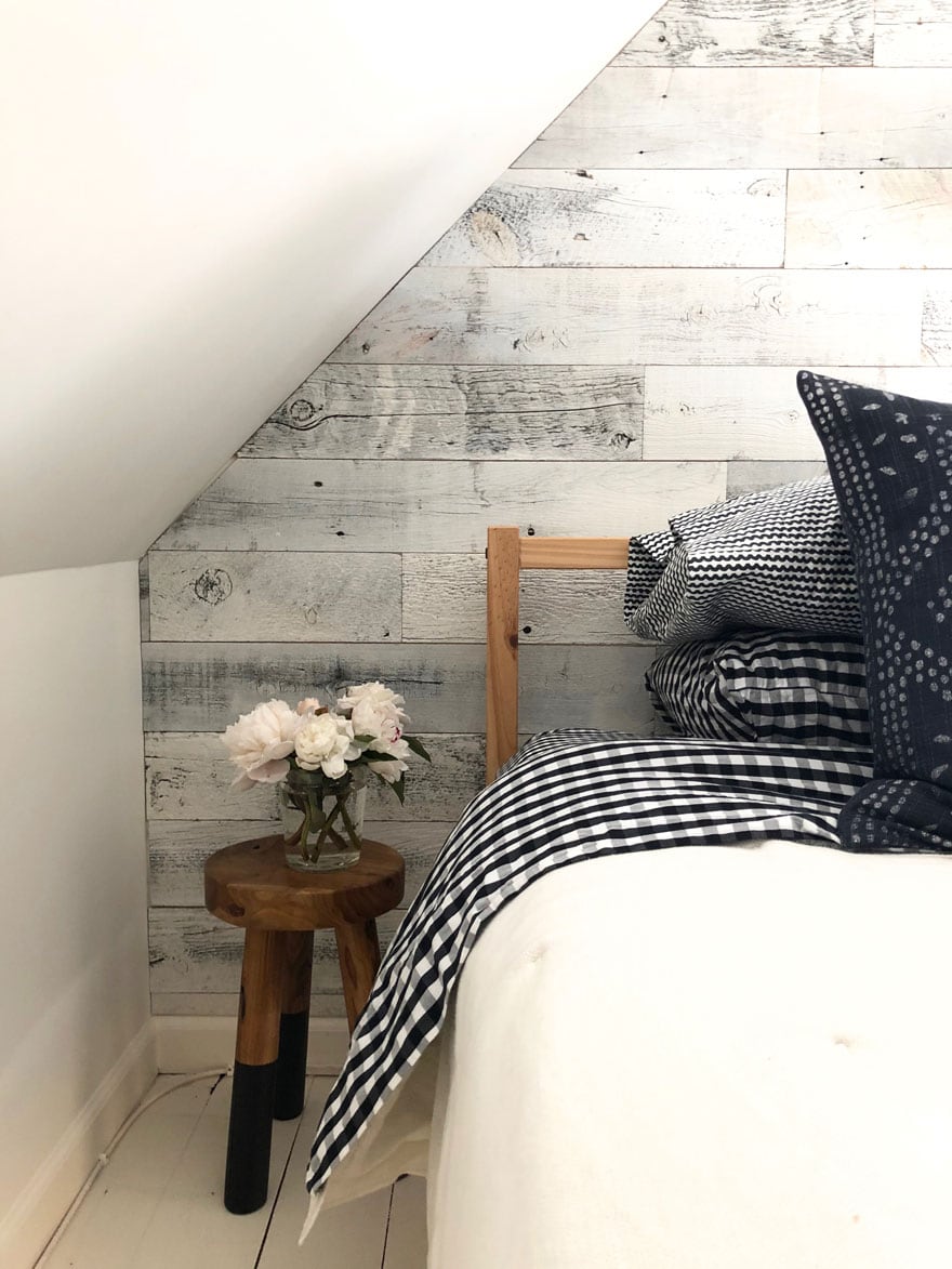 reclaimed wood on walls, stool with peonies next to bed