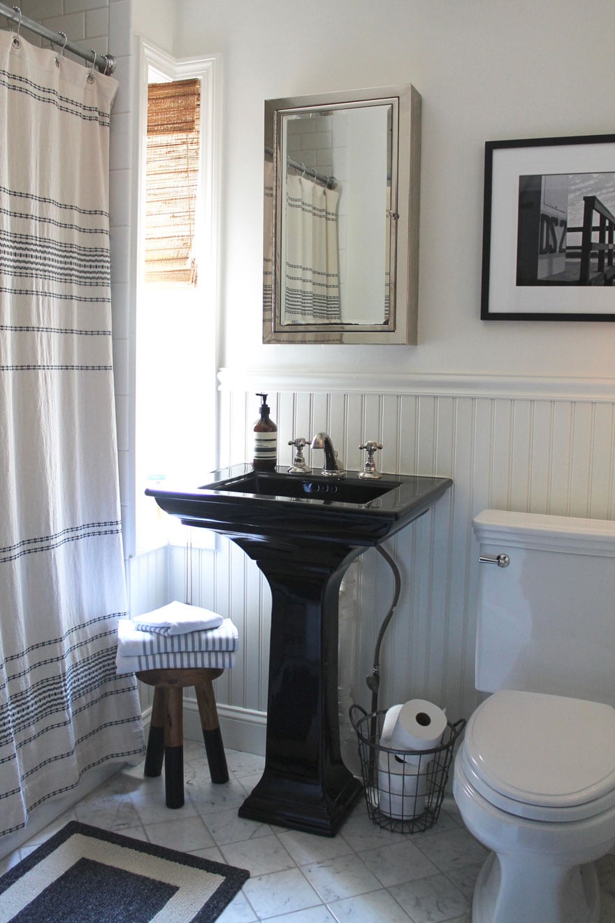 black pedestal sink in bathroom with mirror and narrow window