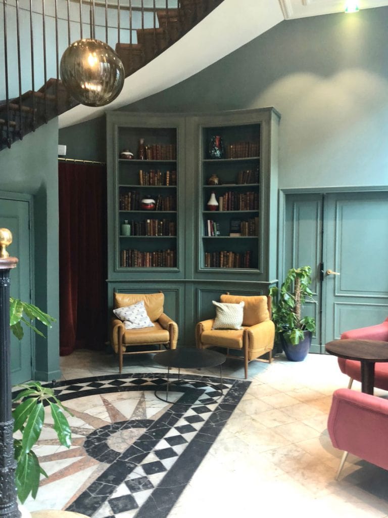 A pair of gold chairs and library bookcases in the lobby of the Hoxton Hotel in Paris.