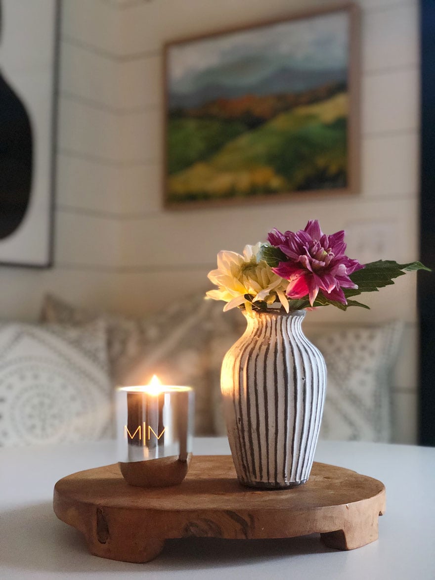 candle and flowers in vase on wood board