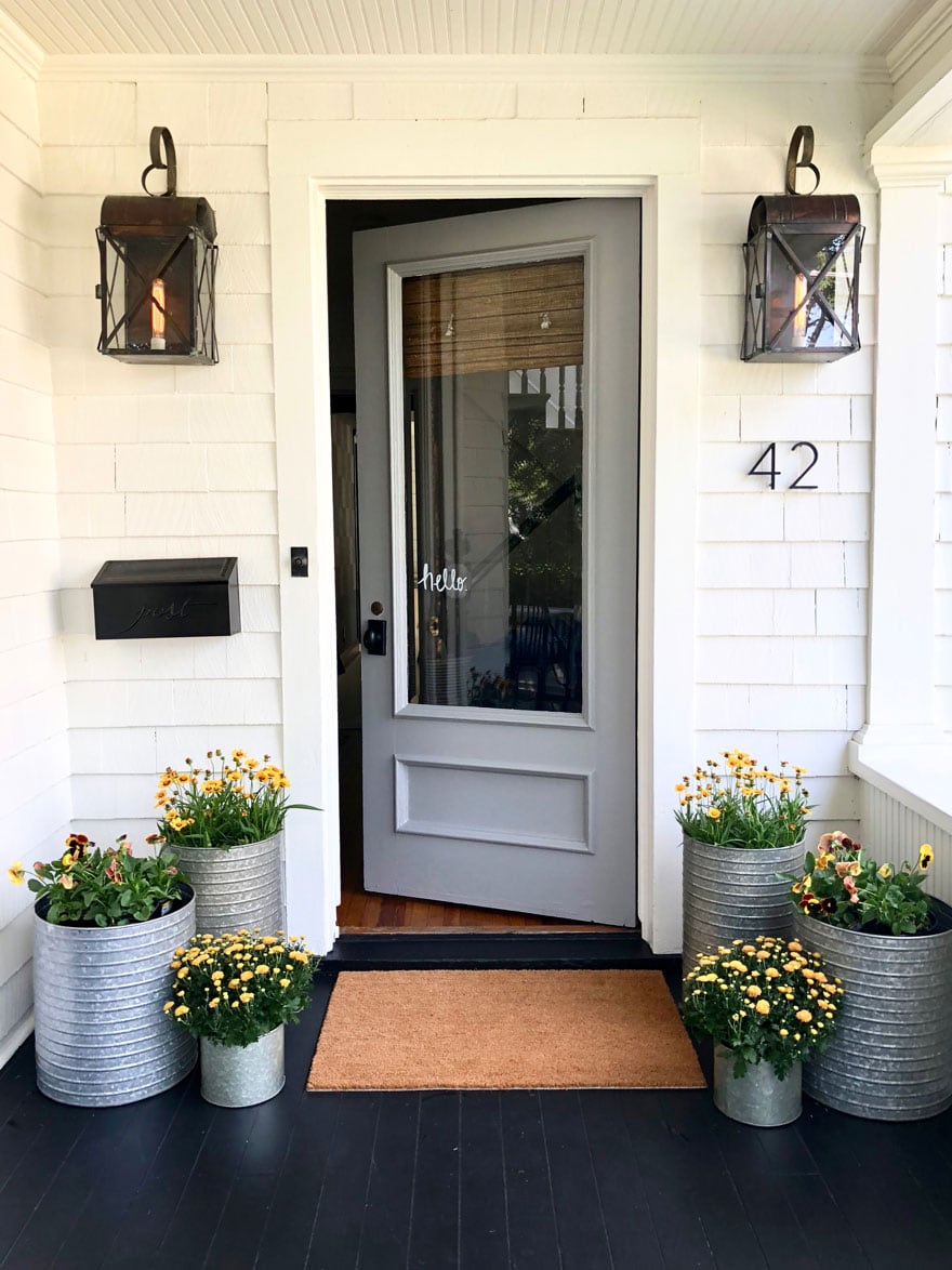 front door on white house with lights and planters 