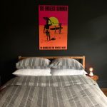 bed in room with black walls, neon poster art