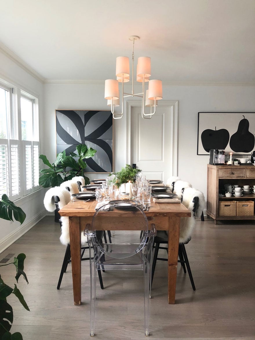 dining room table with place settings in a room with white chandelier and black and gray abstract art