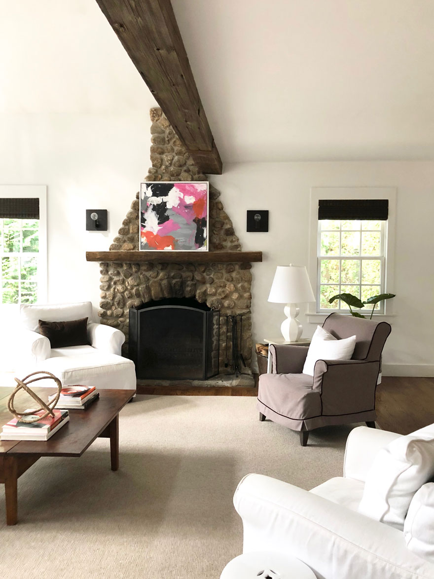 stone fireplace, white walls, windows, chair, lamp, rug