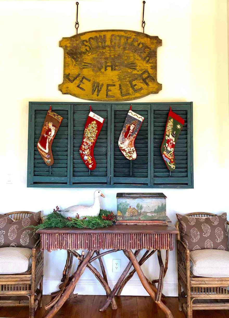 christmas stockings on green shutters with sing plus chairs and twig table