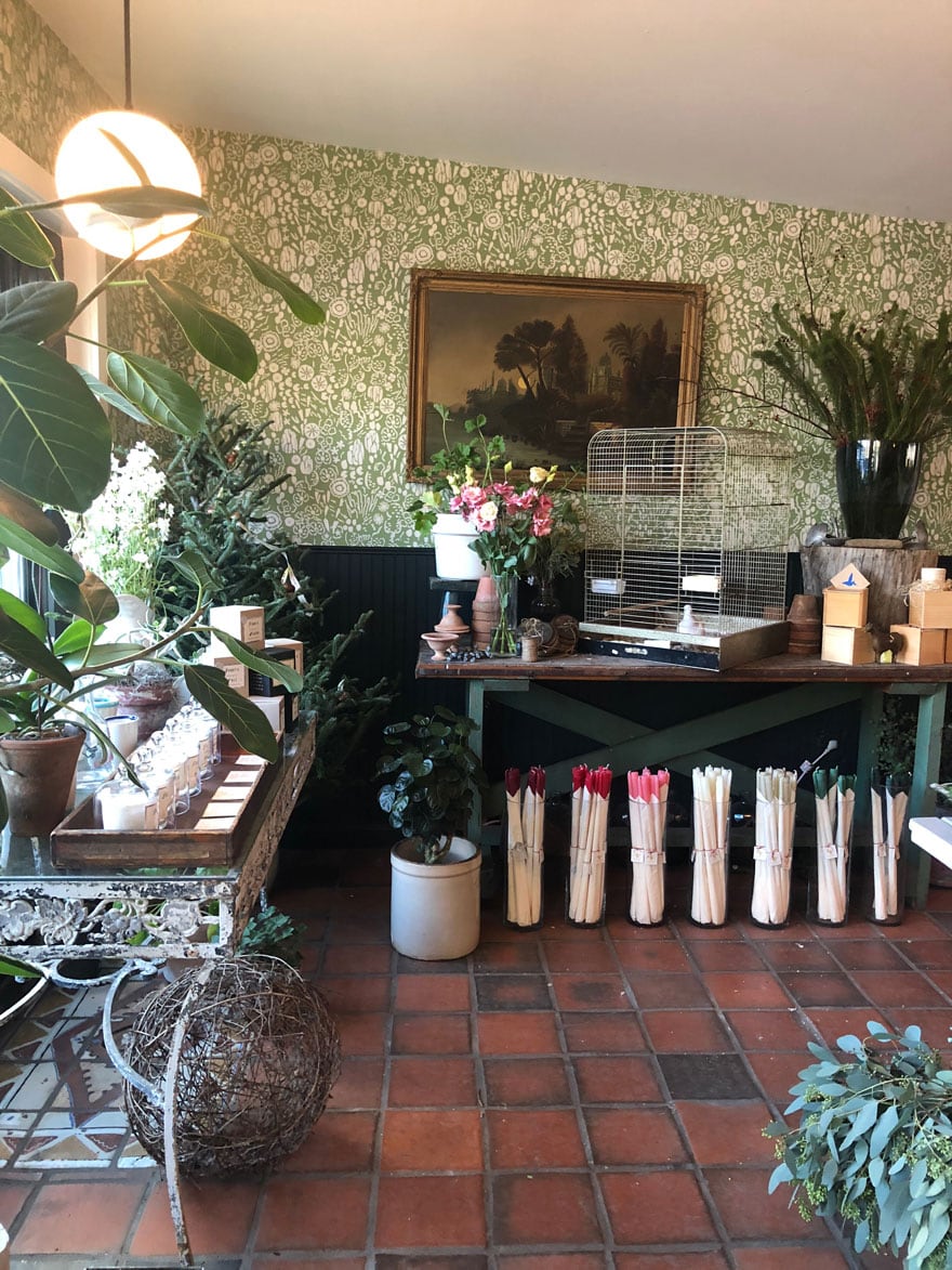 shop with candles, red tiel floor, patterned green wallpaper