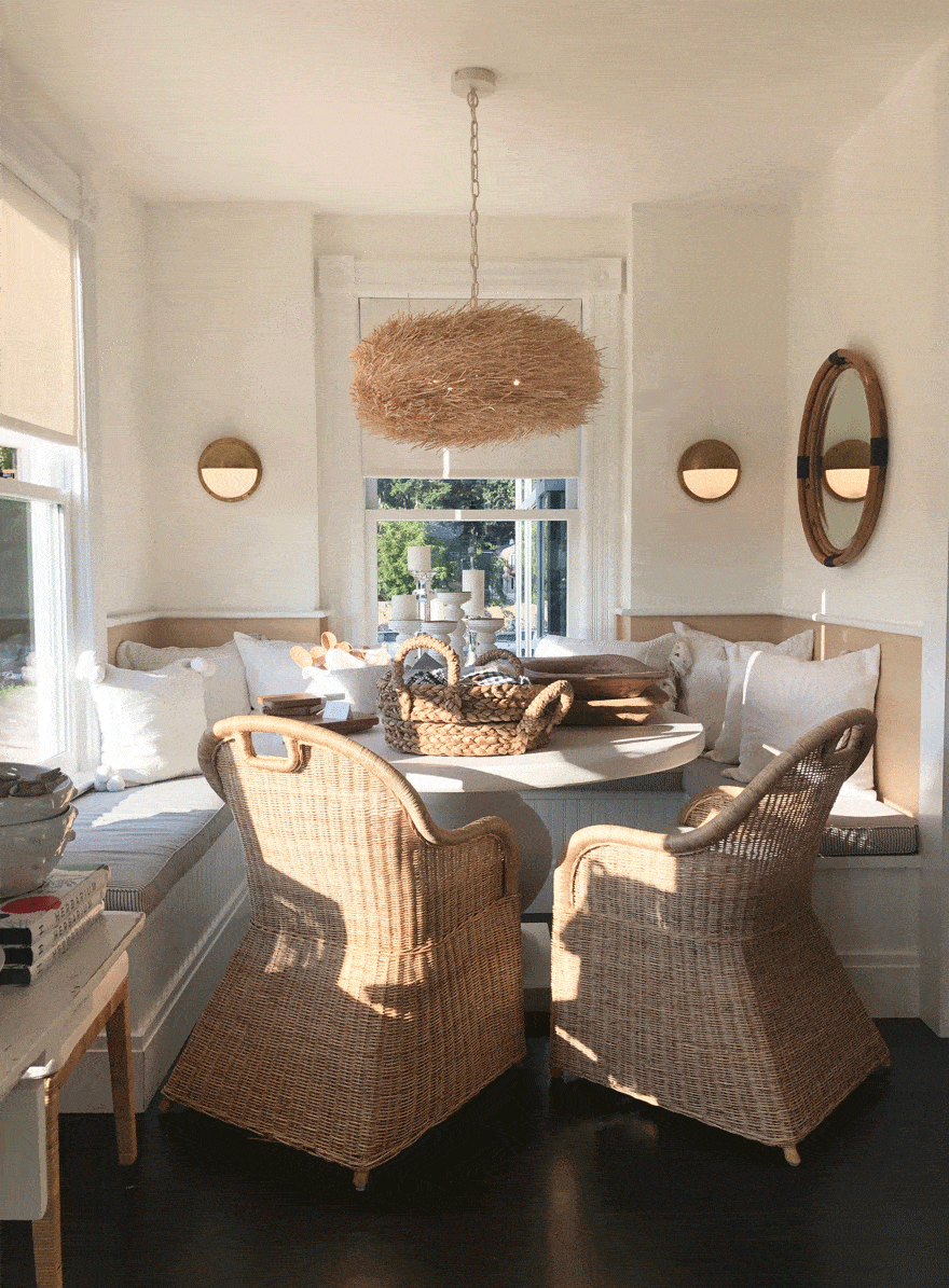 wicker rattan chairs at round table in alcove dining area with pendant light and mirror on wall