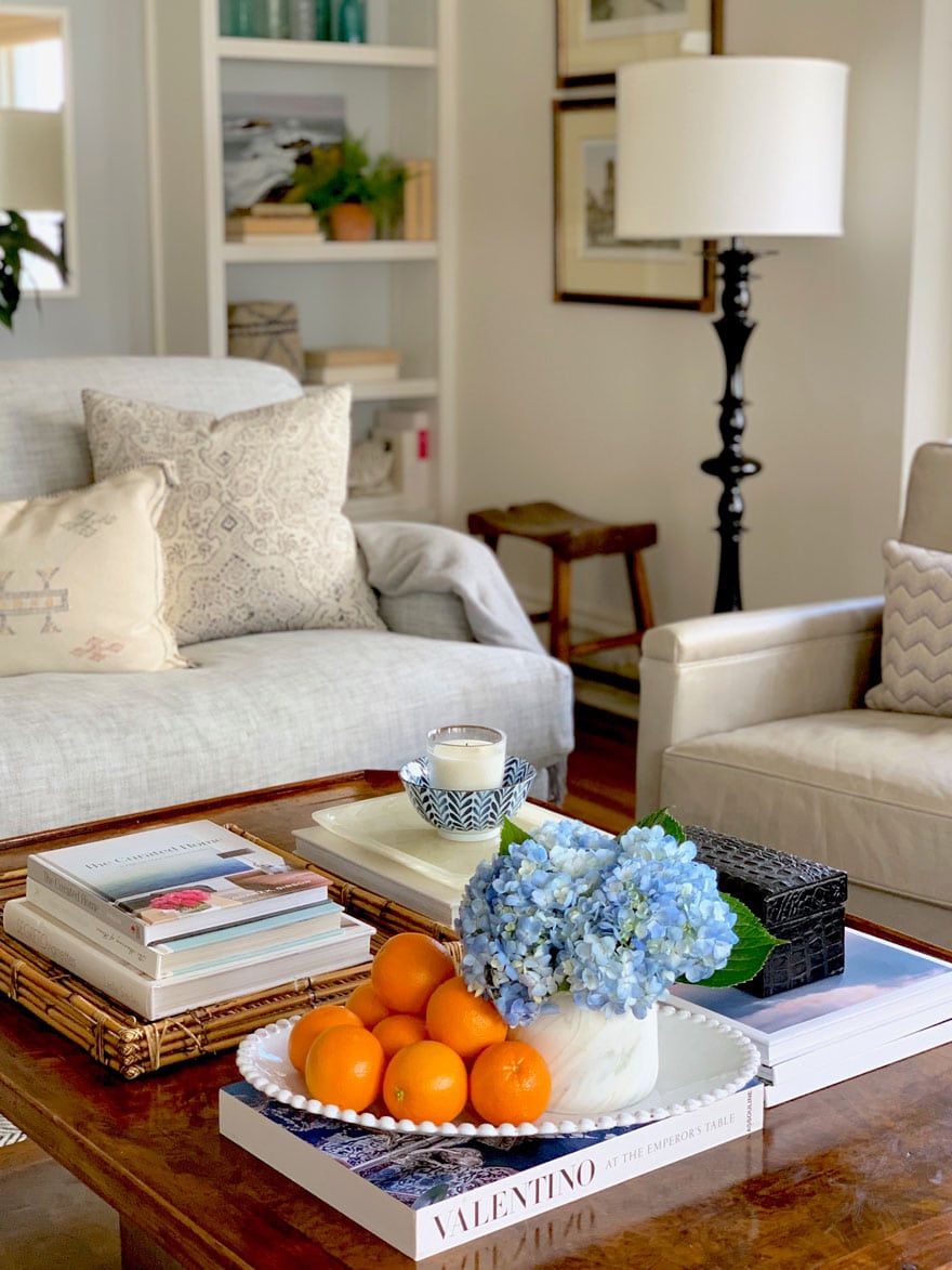 coffee table with oranges, hydrangea. sofa, lamp, art