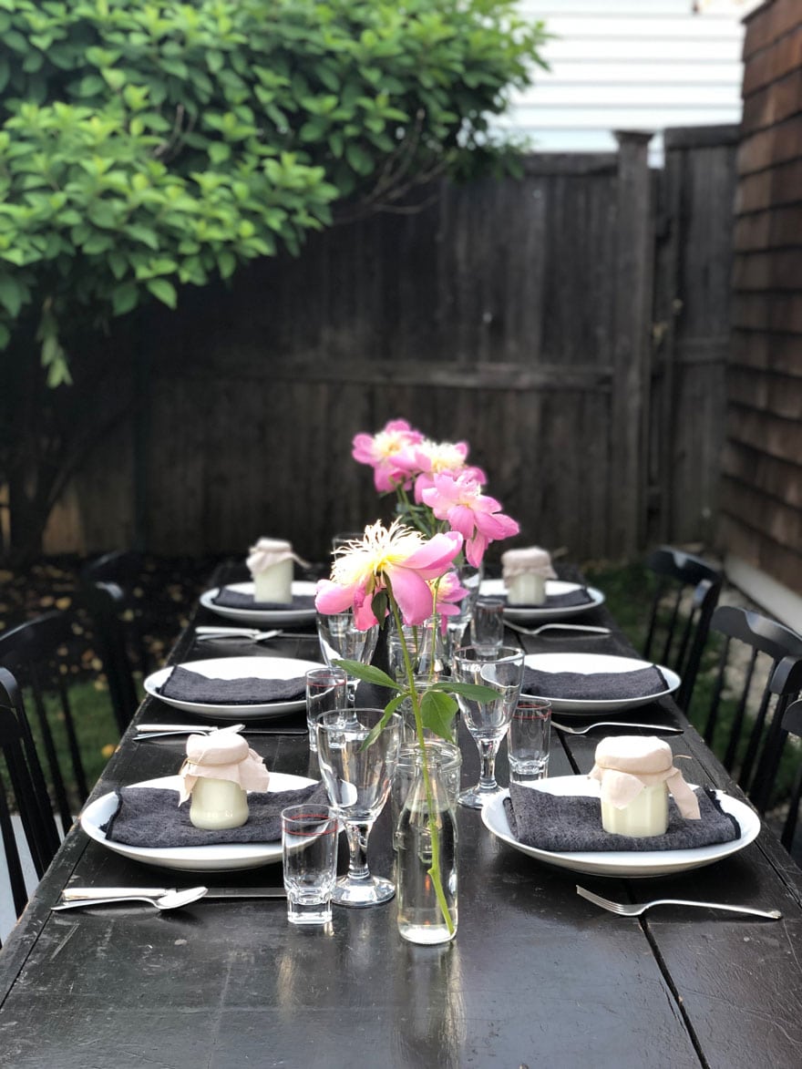 outdoor table, peonies, citronlella candles, clear glassware, bush