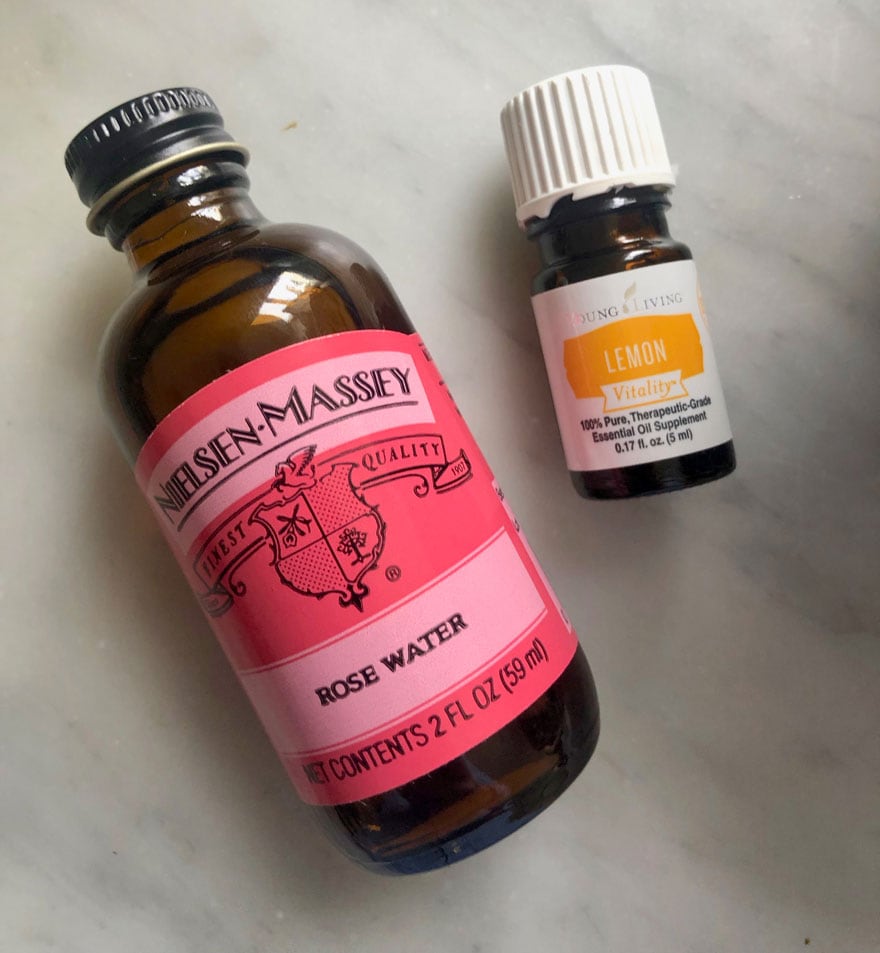 bottle of rose water and lemon essential oil on marble counter
