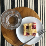 pie on white plate with fork, glass of water on round stool on striped rug