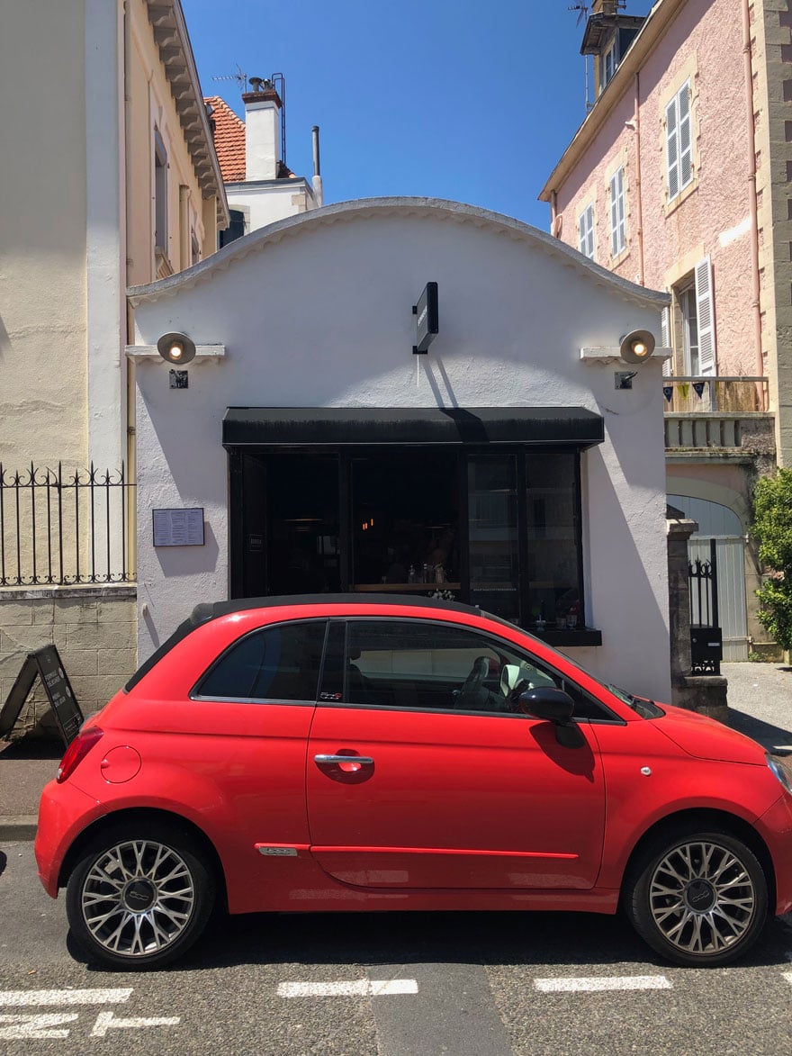 tiny red fiat in from of small restaurant