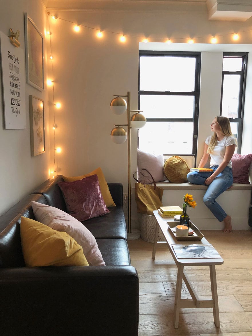 woman sitting on window seat in apartment looking out large window