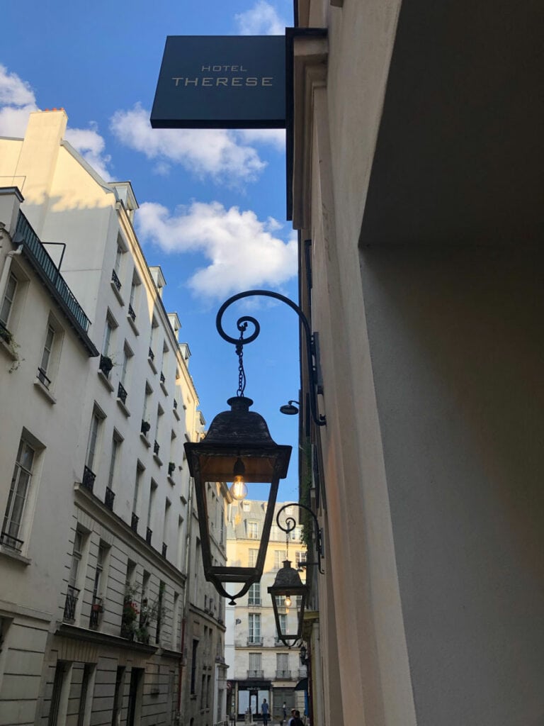 A sign, lantern, street, and sky at the Hotel Therese in Paris. Great European vacations start with Tablet Hotels.