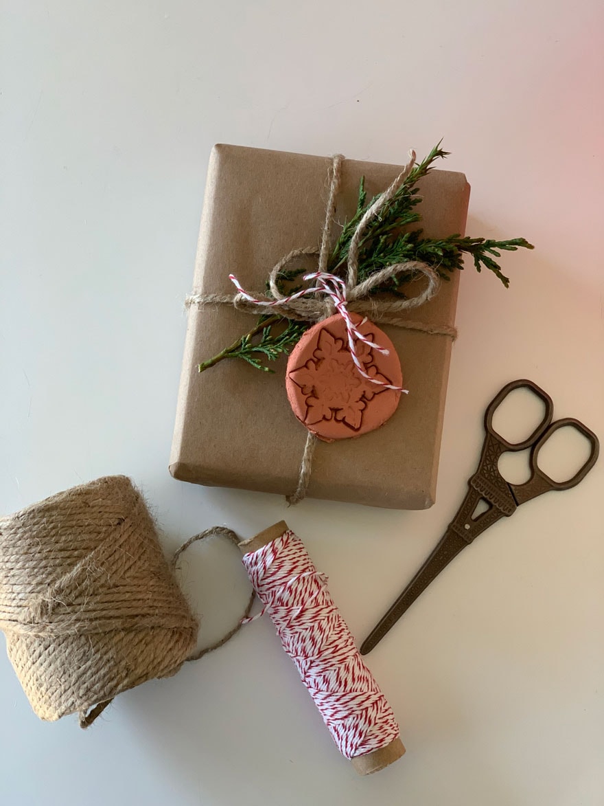 gift with fresh evergreen and clay tag tied up with twine 