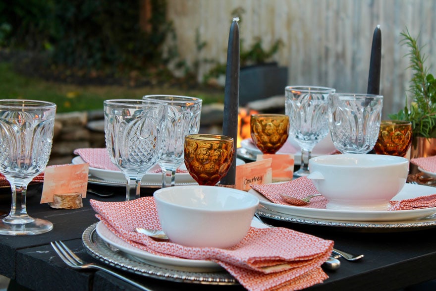 dishes, amber and clear glassware, orange napkins, gray candle