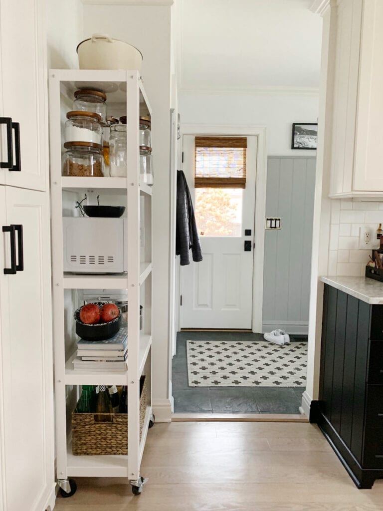 shelf with kitchen supplies, door. rug, handles on cabinets
