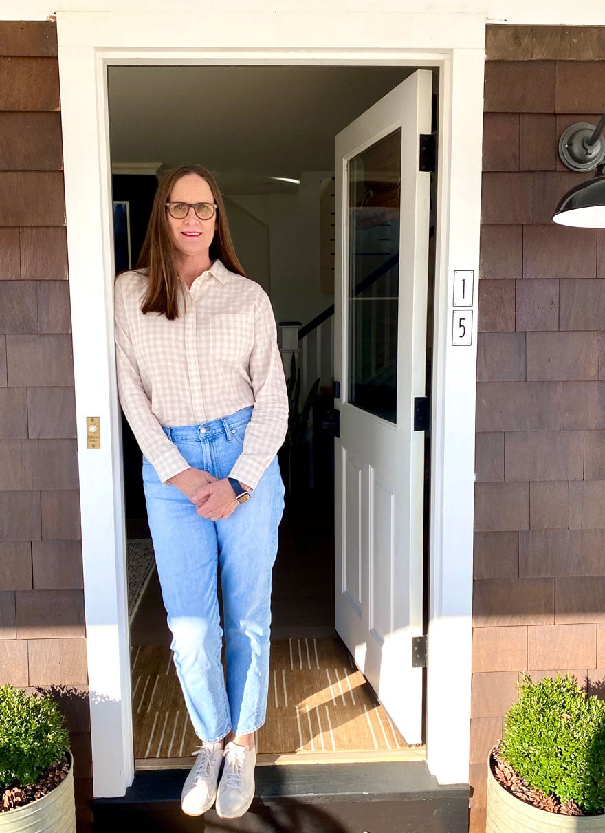 woman wearing tan gingham shirt and faded jeans in doorway