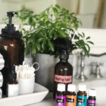 amber spray bottle and essential oils on a bathroom counter with a plant