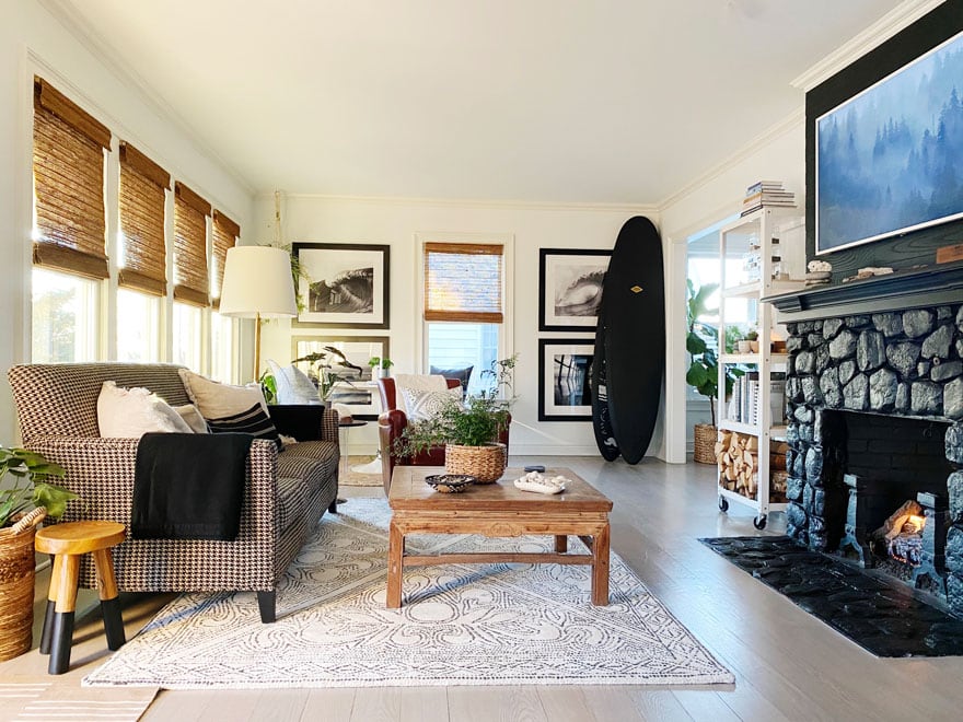 living room with windows, sofa, black surf boards and prints on walk, coffee table, chair, black stone fireplace