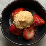 strawberries with vanilla ice cream in a black bowl