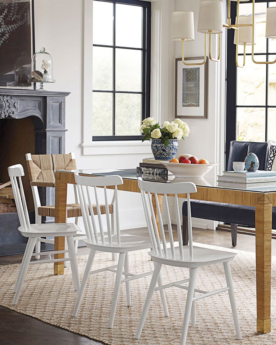 wicker table with white dining chairs in dining room with ornate fireplace