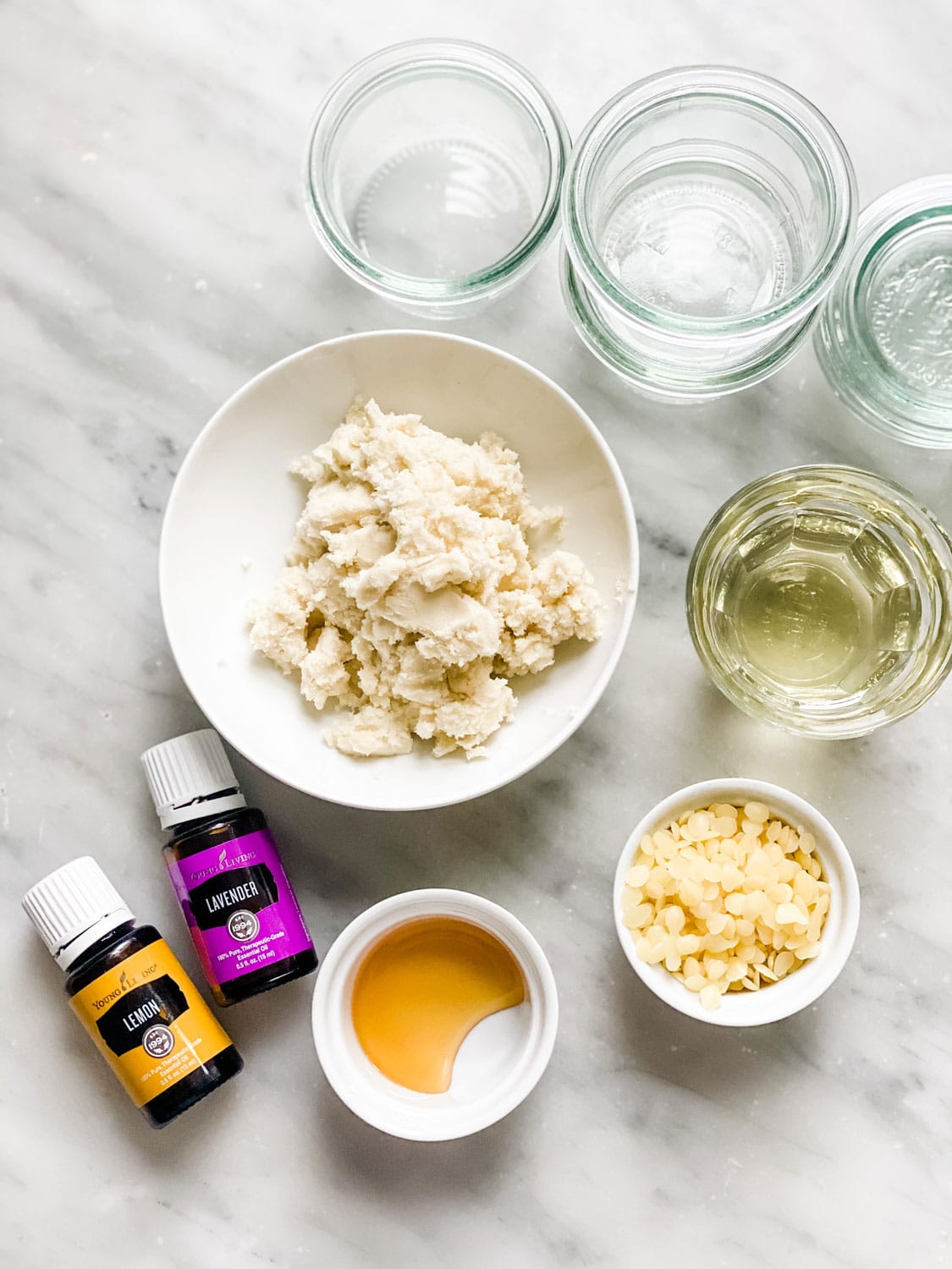 essential oil bottles, ingredients in small bowls on marble counter