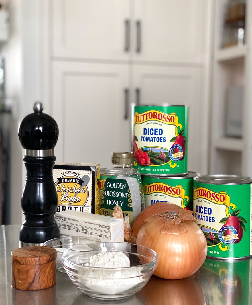 ingredients on counter, tomato cans, onions, pepper grinder