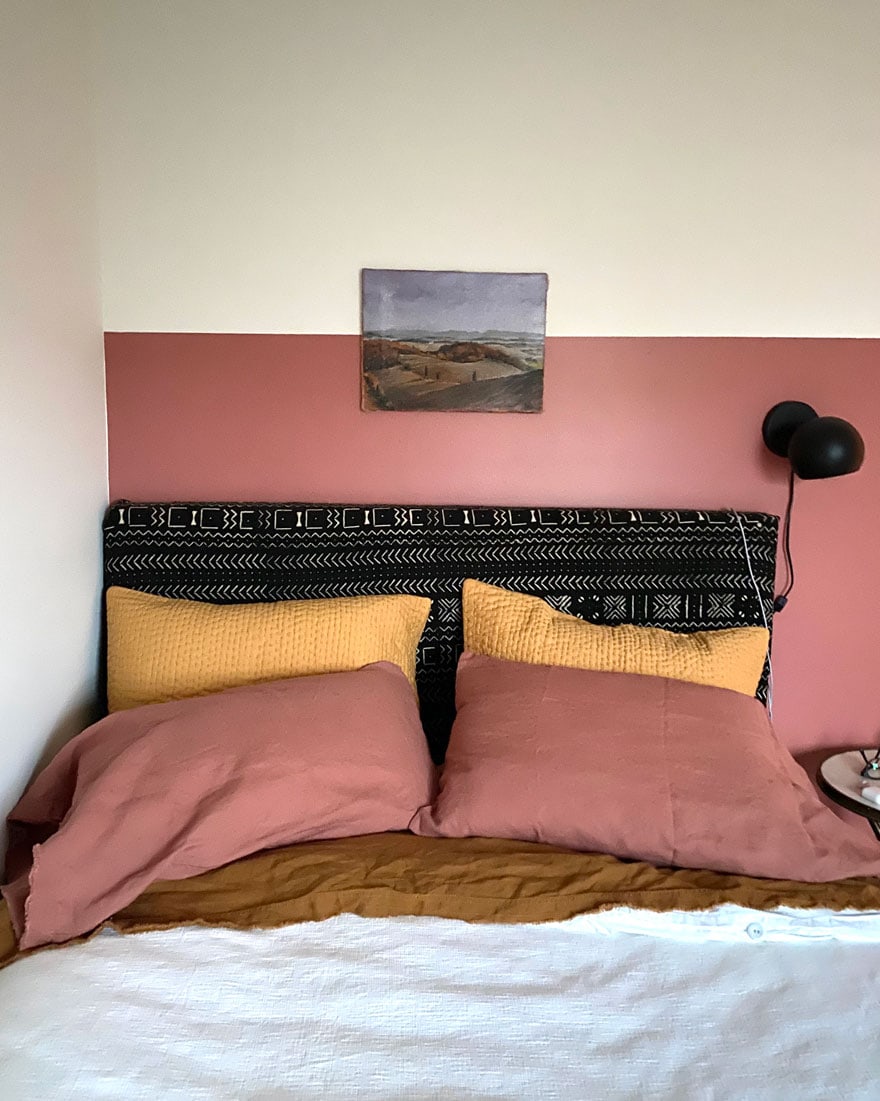 bedroom with black headboard, small paining with 1/2 wall painted pink