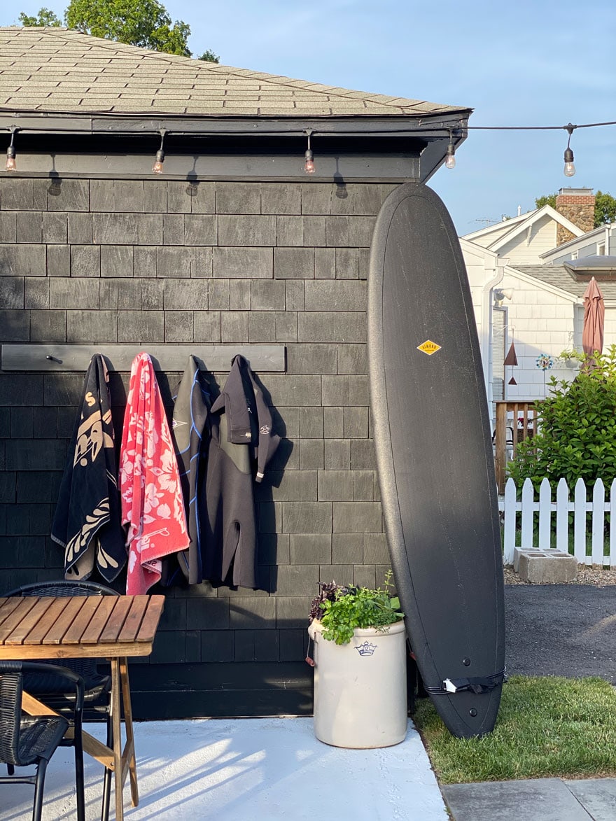 surf board against black house with hooks and towels