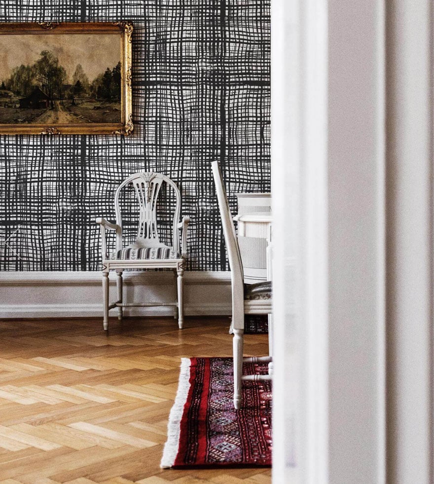 herringbone wood floors, black and white graphic wallpaper, old paintings, chair, rug