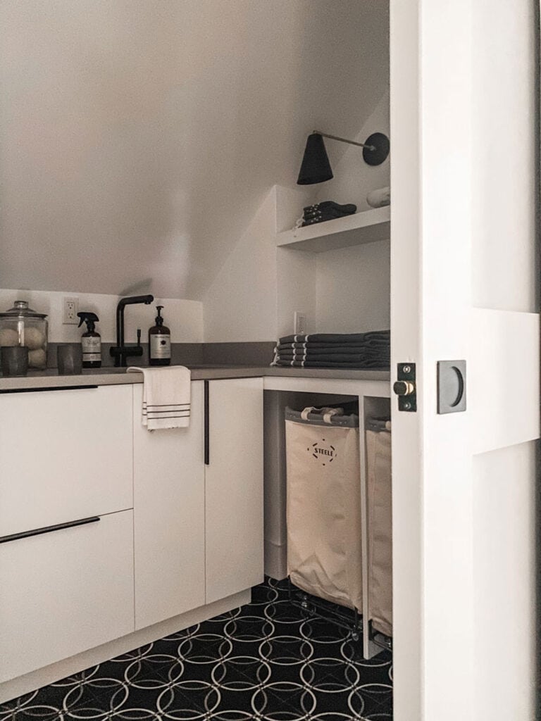 White cabinets, sink, laundry bins. sconces and open shelving have been added to this laundry room remodel.