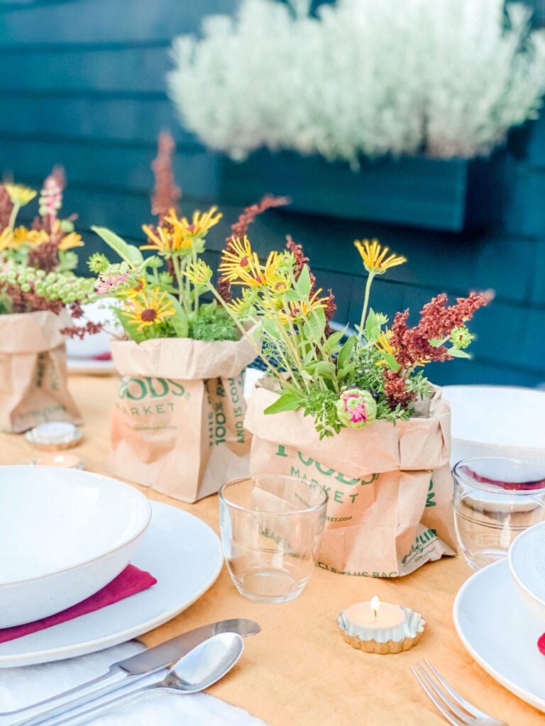 White dishes and plates sit on top of warm, colorful lines withe rustic floral bouquets running down the middle of the table.