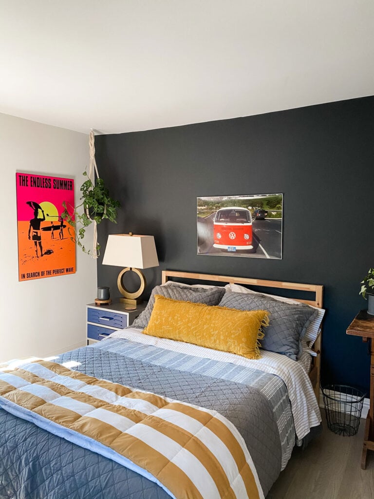 bedroom with black walls, bright colored poster, gray and gold bedding