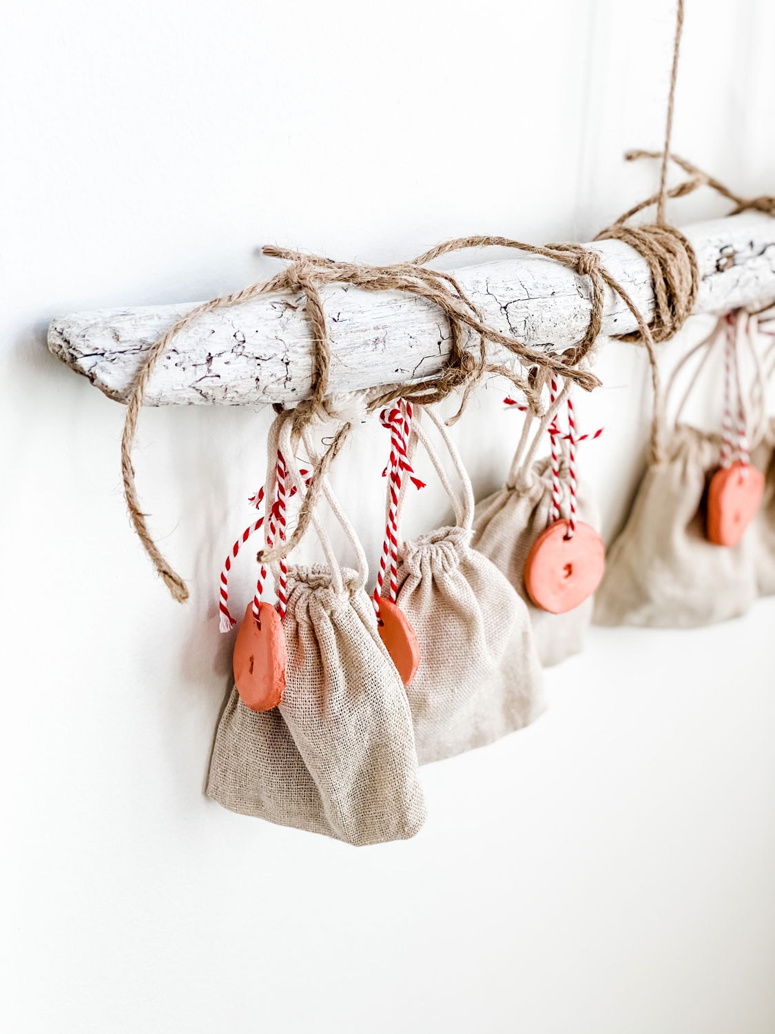 driftwood, greens, bags, clay tags advent calendar on white wall