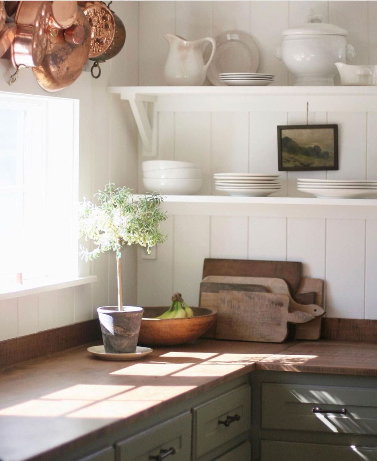 Megan Miller's kitchen with open shelving, copper pots, topiary and art