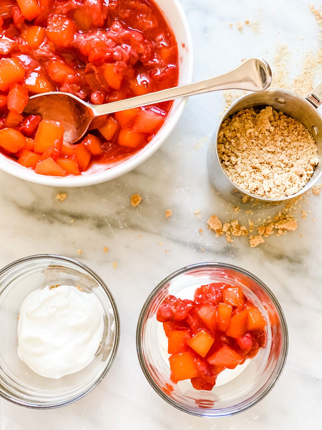 parfaits with yogurt and mixed colorful fruit, graham cracker crumbs in measuring cup