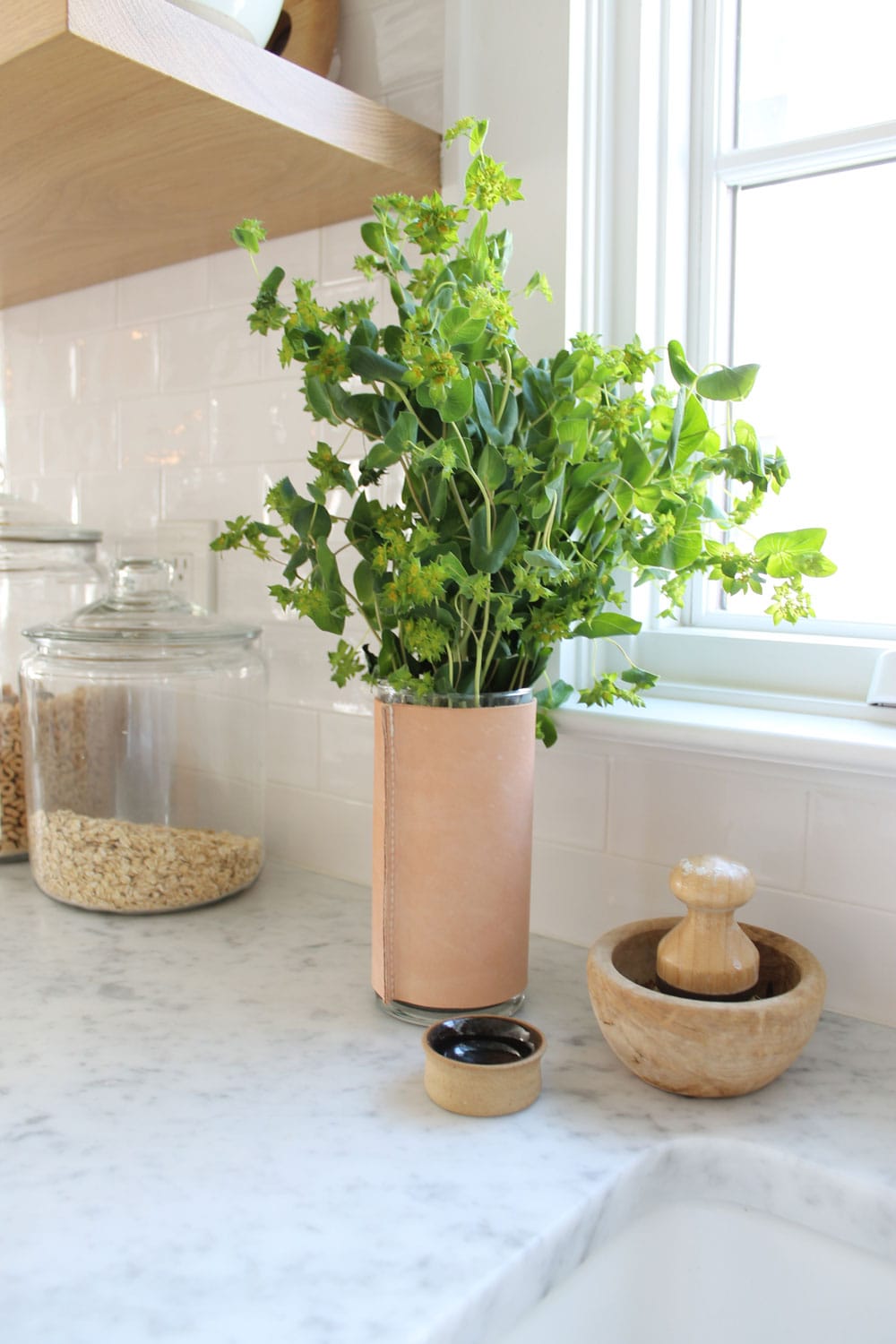 leather vase with greens, dish brush in wood bowl