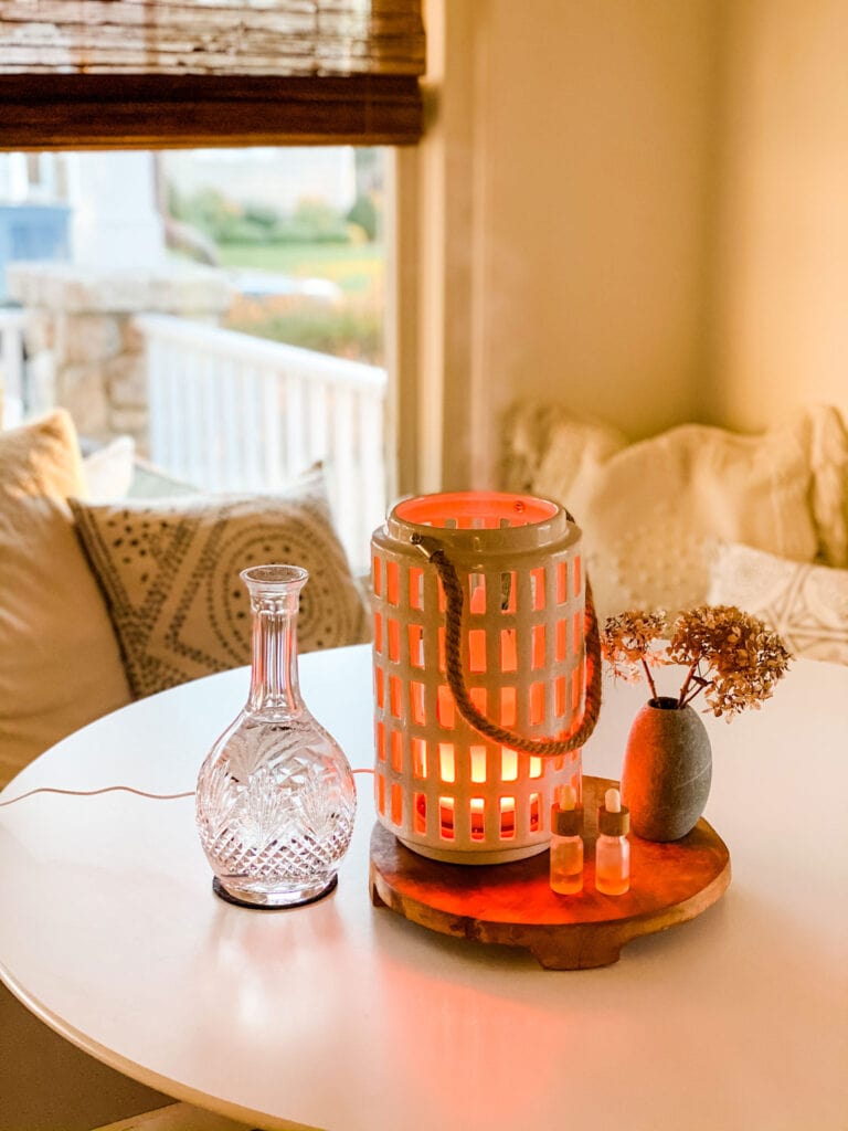 ceramic lantern, crystal decanter, round wood trivet on table