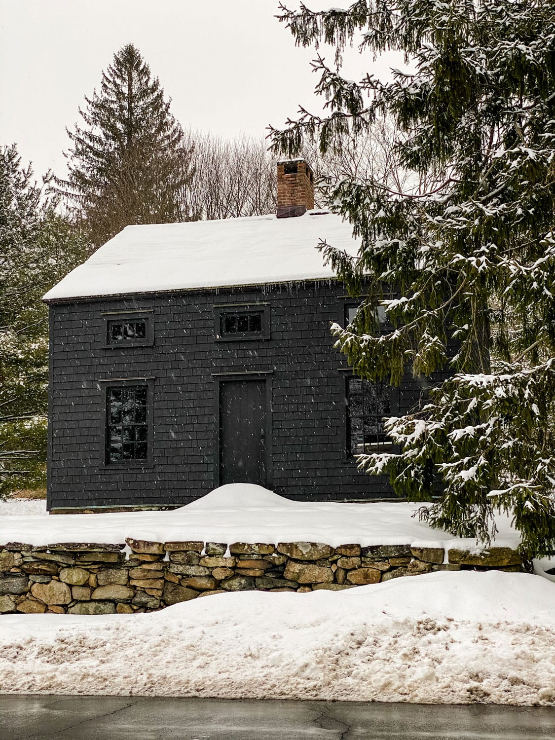 black house with stone wall, snow