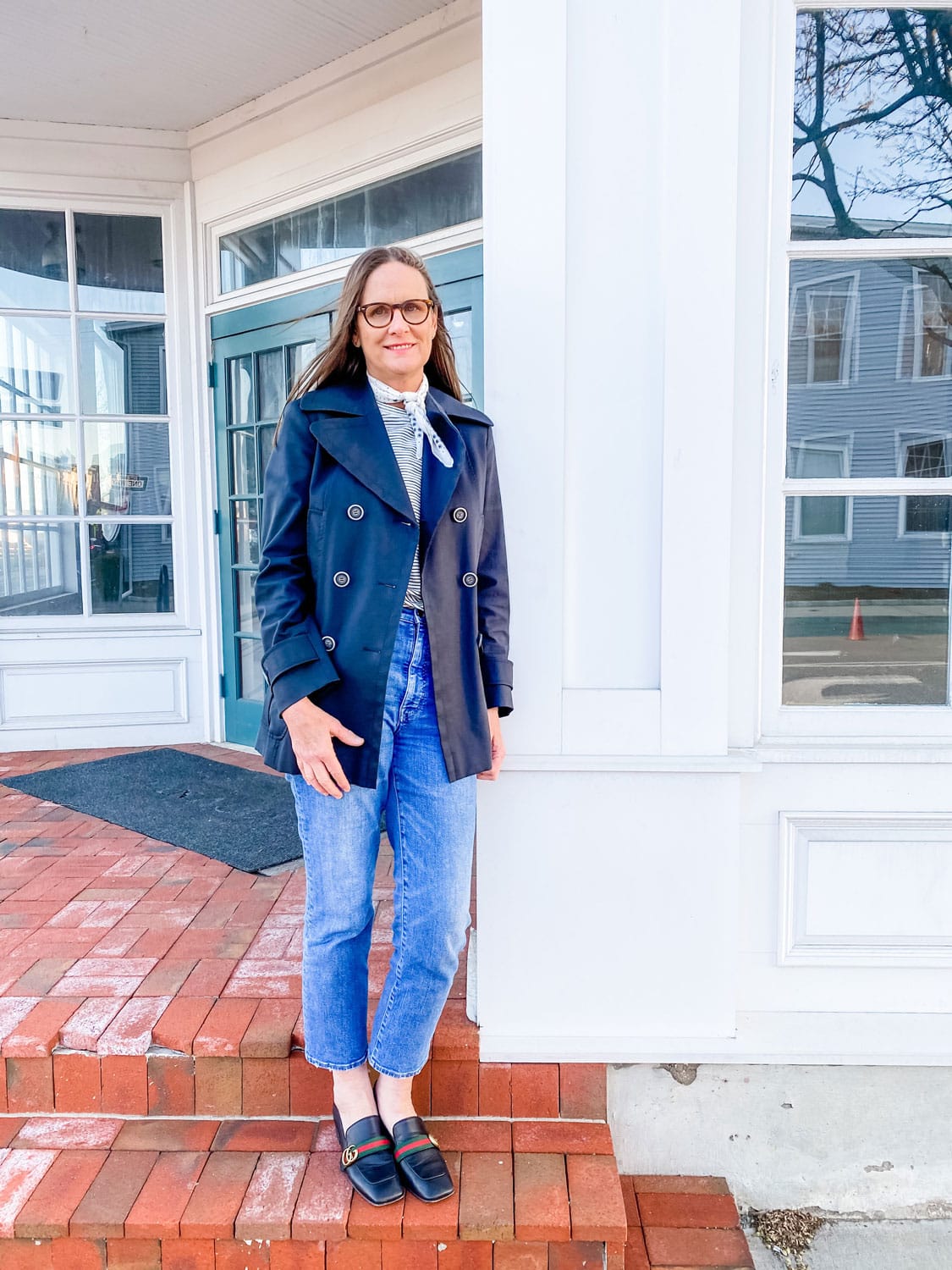 woman standing on stoop in black coat and jeans