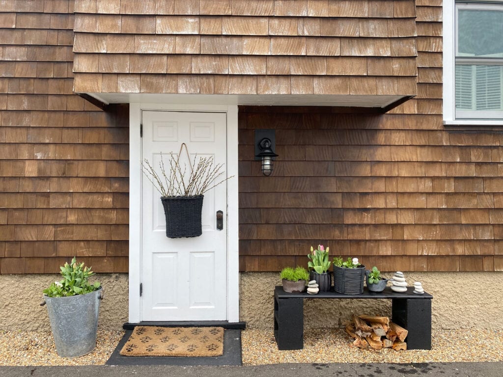 white door, shingled cottage, black bench, flowers