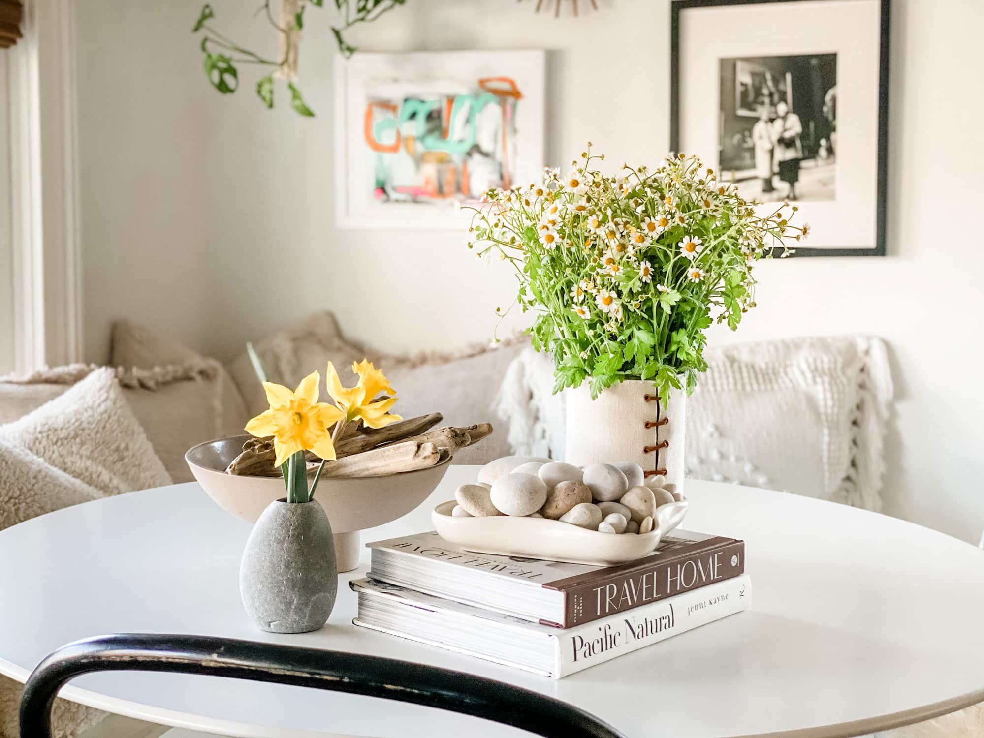 vase with chamomile, books and rocks/driftwood on white table