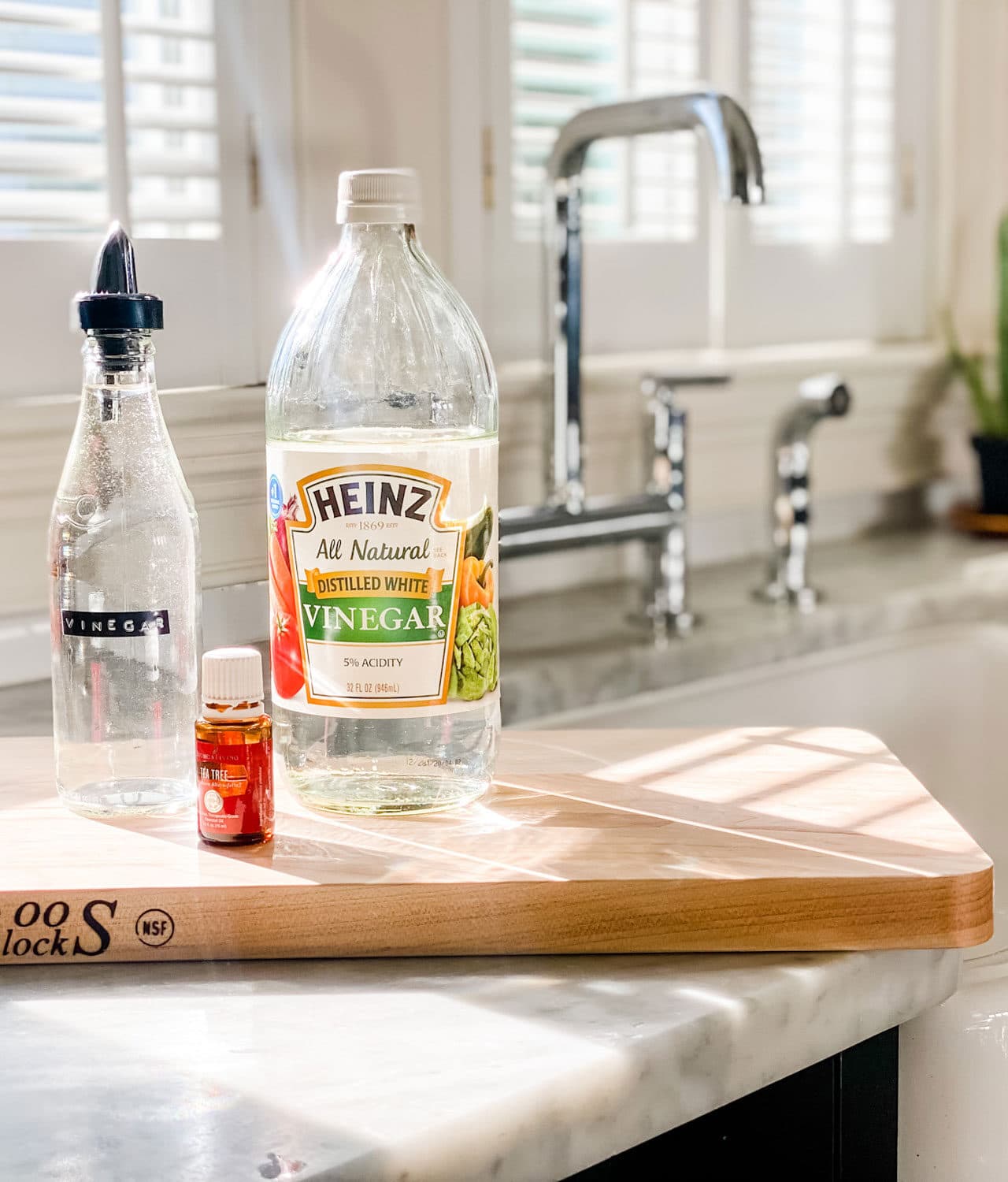 wood cutting board, vinegar, clear bottle and tea tree